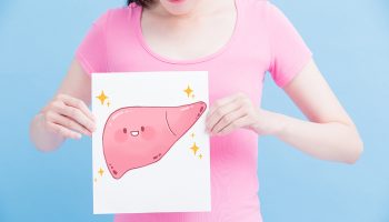 A woman in a pink shirt holding a cartoon drawing of a liver in her hand