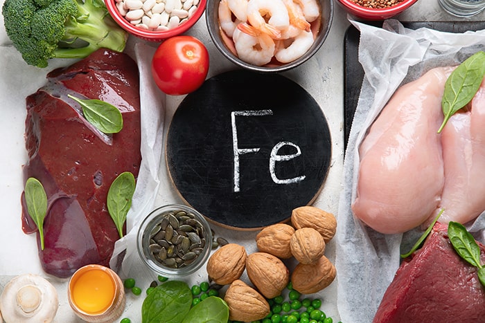 A black plate with a written chemical symbol ‘Fe’ in the middle of iron-rich food ingredients 