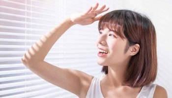 Woman reacting happily to sun exposure from her window blinds