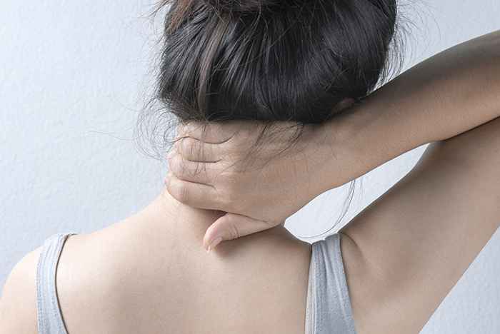 A woman putting her hands on her back, indicating she suffers from back pain