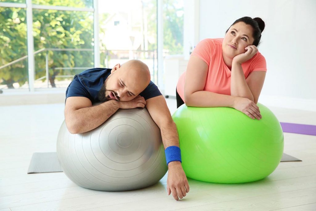 An overweight couple rest after finishing their exercise at the gym