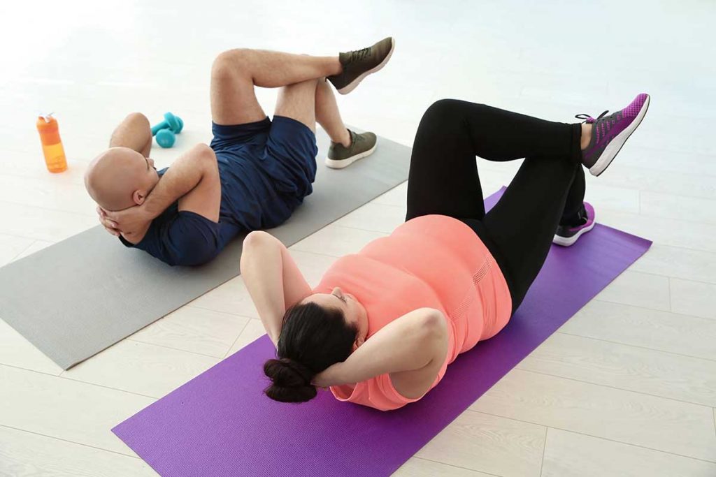 An overweight man and woman exercising on their individual mat
