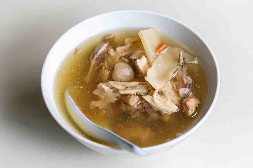 Chicken soup with American ginseng, longan and goji berries served in a white bowl