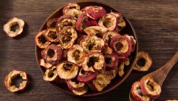 Dried hawthorn berry slices in a bowl on a wooden background