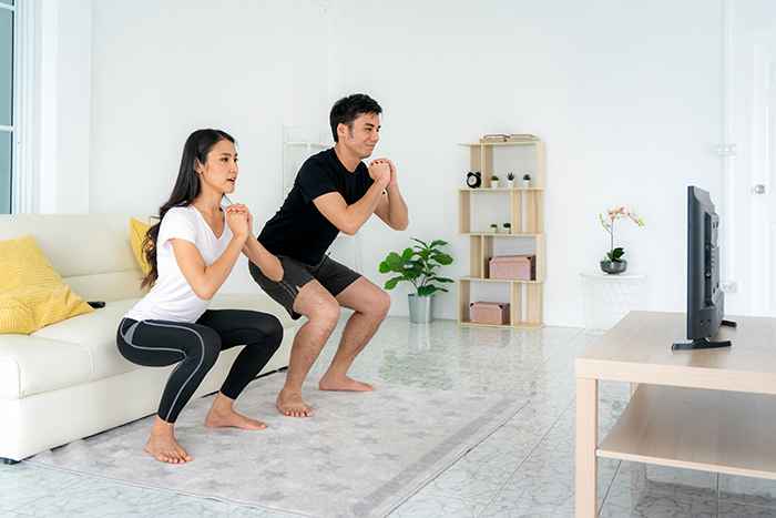 Man and woman happily exercising together at home