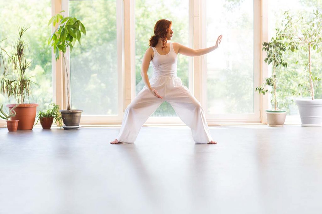 Woman performing a taichi pose indoors