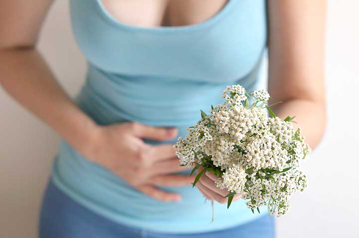 Woman holding flowers with the other hand on the belly