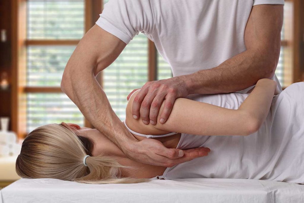 Chiropractor performing back adjustment treatment on a patient