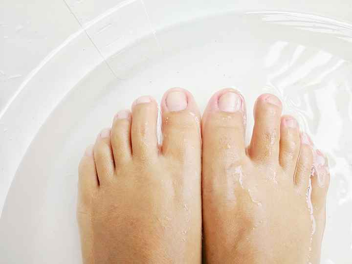 Top view of feet soaking in a small tub of water