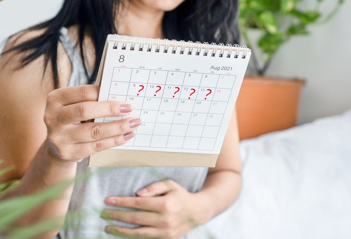 An Asian woman looking at a calendar to track her irregular periods