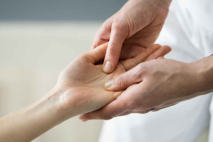 Therapist applying acupressure on a woman’s hand
