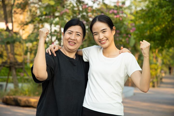 Mother and daughter standing outside smiling happily with victory gestures