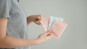 Woman holds three menstrual pads in her hand.