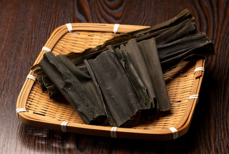 Dried kombu seaweed sheets in small tray on table