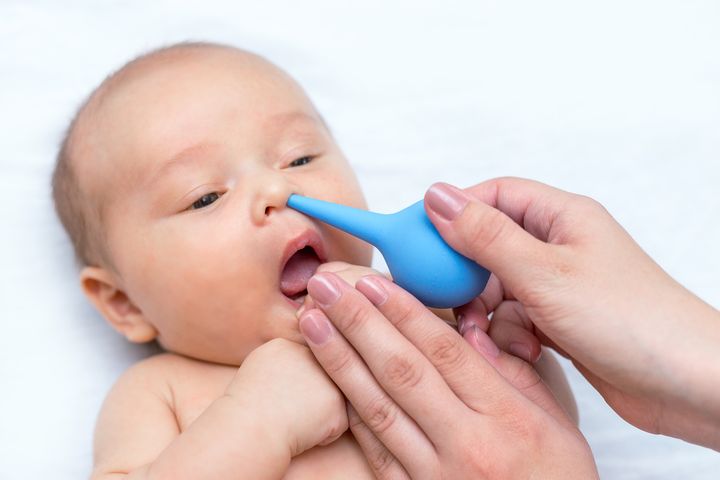 A mother cleaning a baby’s nose with nasal aspirator