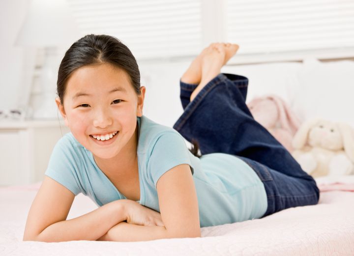 A young girl happily lying on her bed