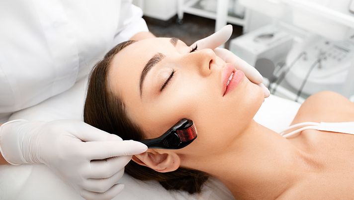 Woman lying down while dermatologist performs micro needling on her face