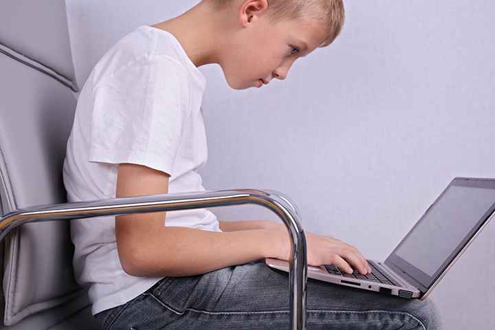 Children bad poor sitting posture. Boy using laptop computer.