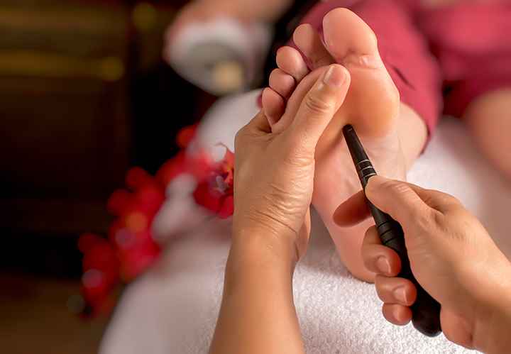 A lady getting an acupressure massage with a massage stick on her foot
