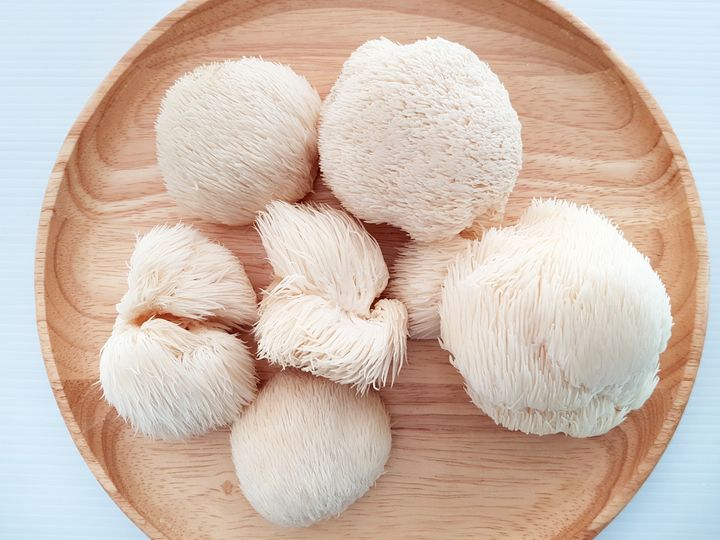 Raw Lion’s Mane mushrooms placed on a round, wooden bowl.