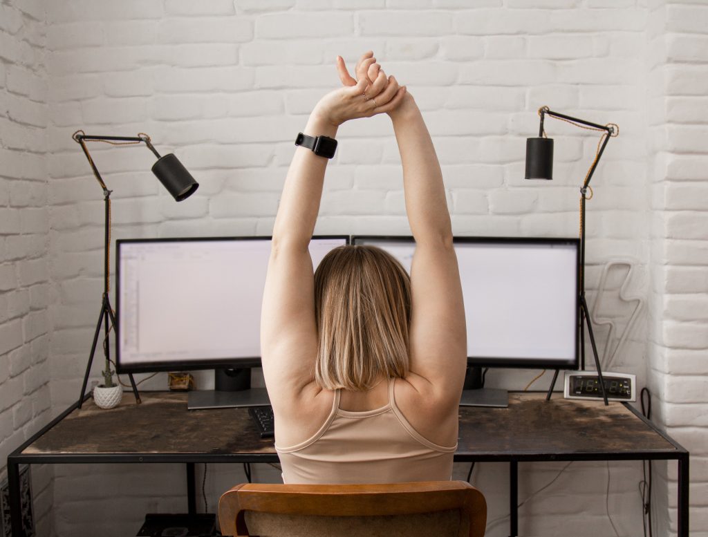 Caucasian woman stretching at her desk
