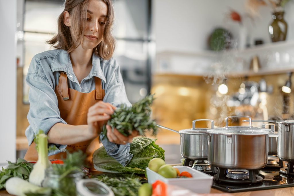 A woman cooking leafy green vegetables for healthy diet