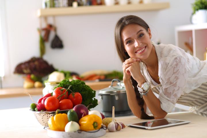 A young woman smiling as she's cooking a DASH diet meal plan