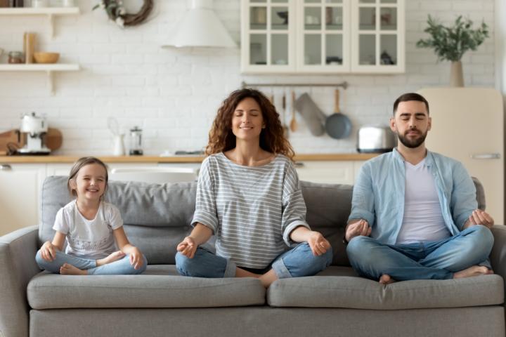 A father, mother, and daughter doing meditation at home