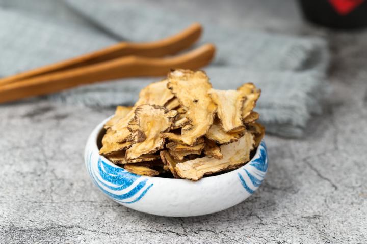 A dried angelica sinensis inside a ceramic white and blue bowl to treat digestive problems