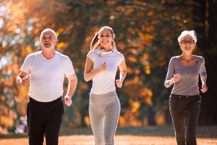 A senior man jogging with a young fit woman and senior woman in the park