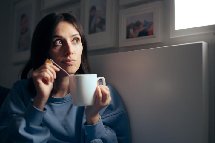 A young woman sitting in bed with a cup of herbal tea