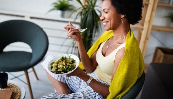 A happy woman eating a healthy meal in her home as part of her anti-inflammatory diet