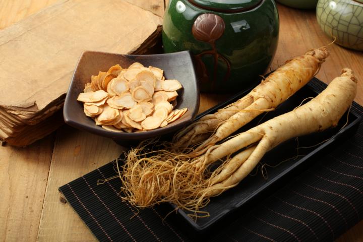 A plate of sliced asian ginseng root with two whole ginseng roots on a plate